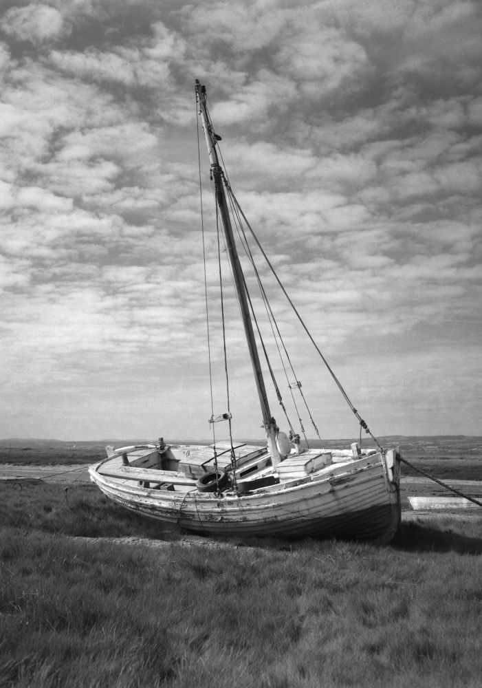 Black and white photo of an old shrimper moored on a marsh bank