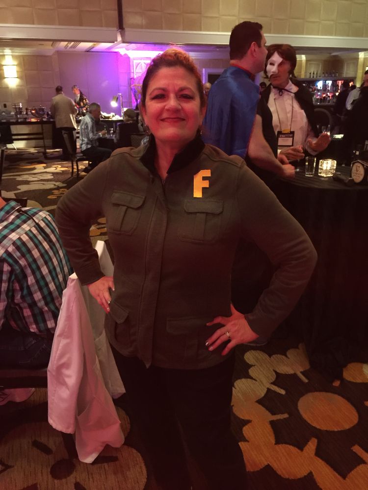 Woman dressed in a green coat with an f letter in yellow. Mary Jo Pehl costume from MSTK3000.