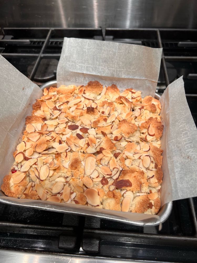 Cranberry almond brownie in an 8” cake pan with parchment paper sling.