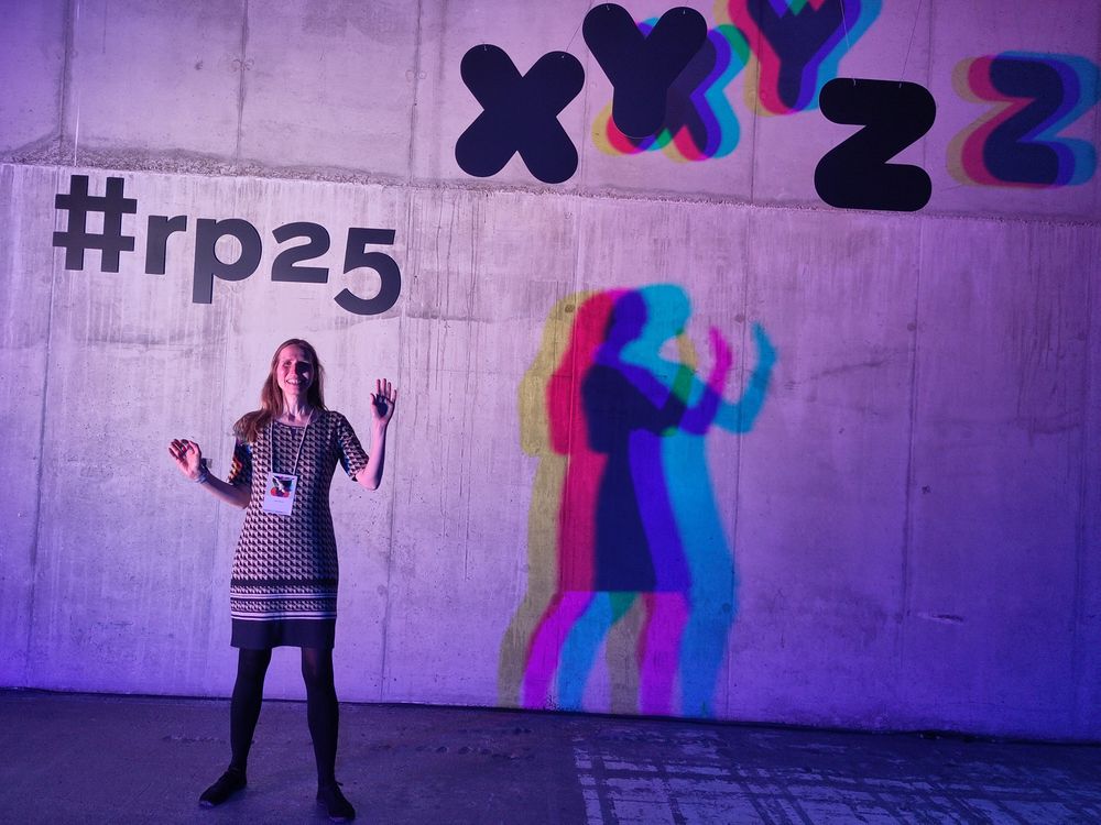 Nele vor einer Wand mit Regenbogen Silhouette - dahinter der Hashtag rp25
