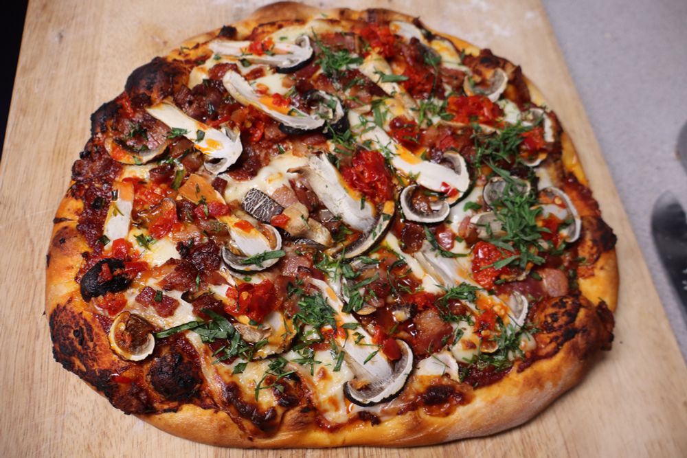 Homemade pizza with homegrown mushrooms and tarragon, bacon, mozz, parm, and Calabrian chili