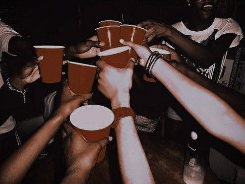 a party scene, a crowd of people raising red solo cups in a toast