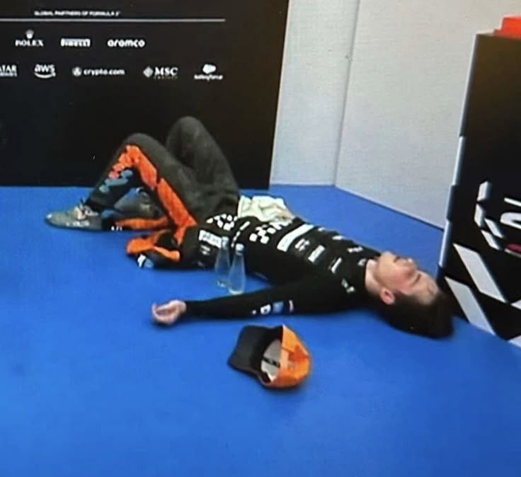 oscar piastri laying on the floor of the cool down room exhausted after a race 