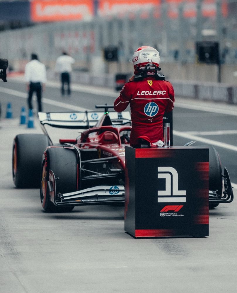 Charles leclerc sitting on the p1 box thing in Parc fermé after finishing on pole in Hungary. He is facing away from the camera, looking at his car. 