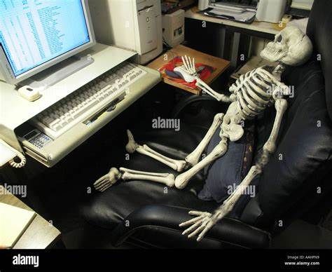 a skeleton sitting at a computer desk