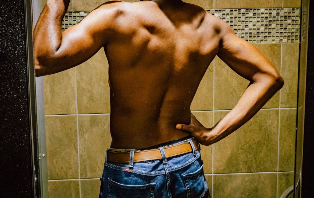 Photo of me without a shirt on in a bathroom appreciating muscle gains