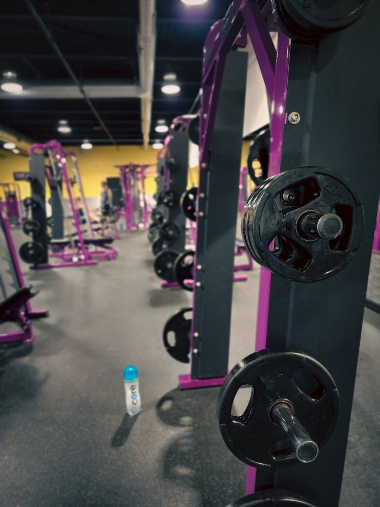 Photo of a smith machine inside of a gym with a bottle of water on the floor
