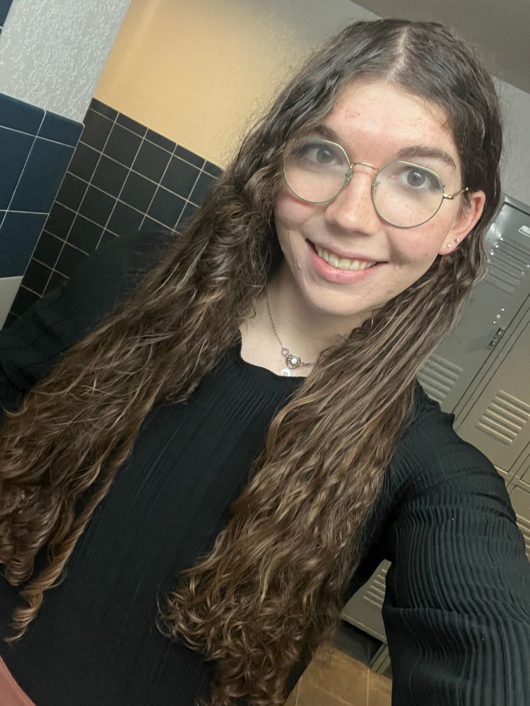 puddle selfie with faer hair brushed down and the light reflecting in the moon on faer collar