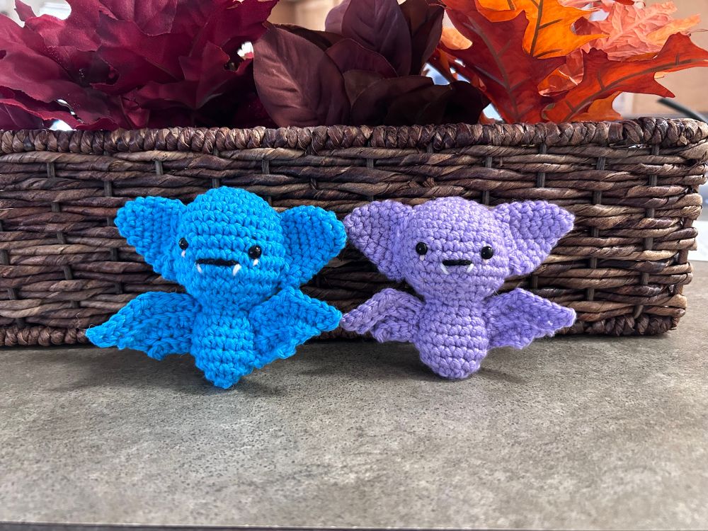 Two crocheted amigurumi bats, one purple and one turquoise. The kit is called “Creepy Crochet Kit” by Chartwell Books