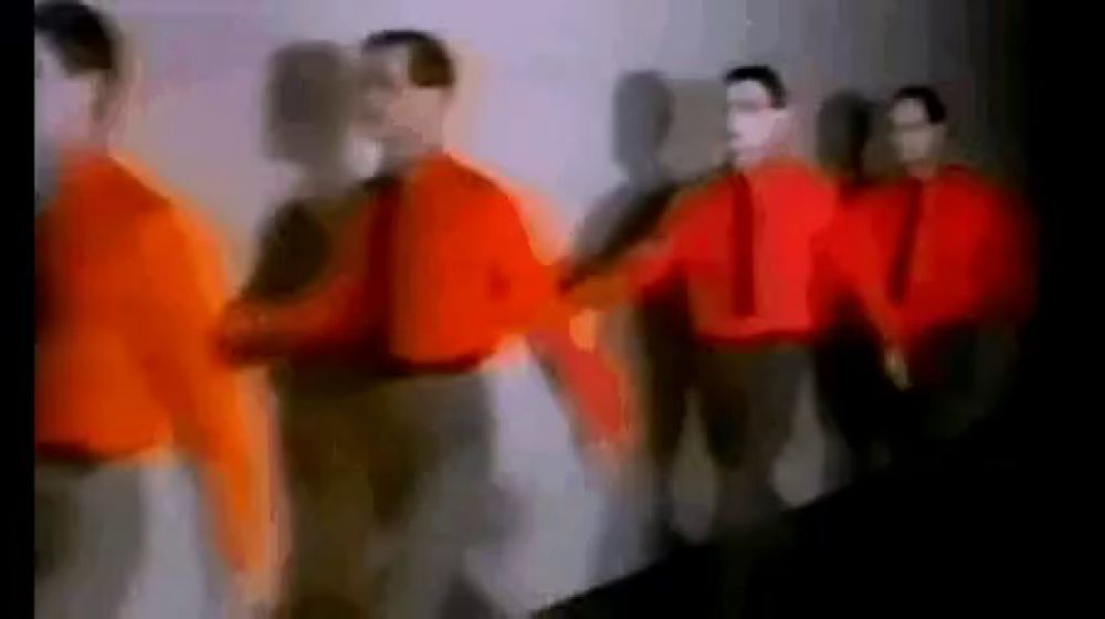 a blurry picture of a group of people wearing red shirts holding hands .