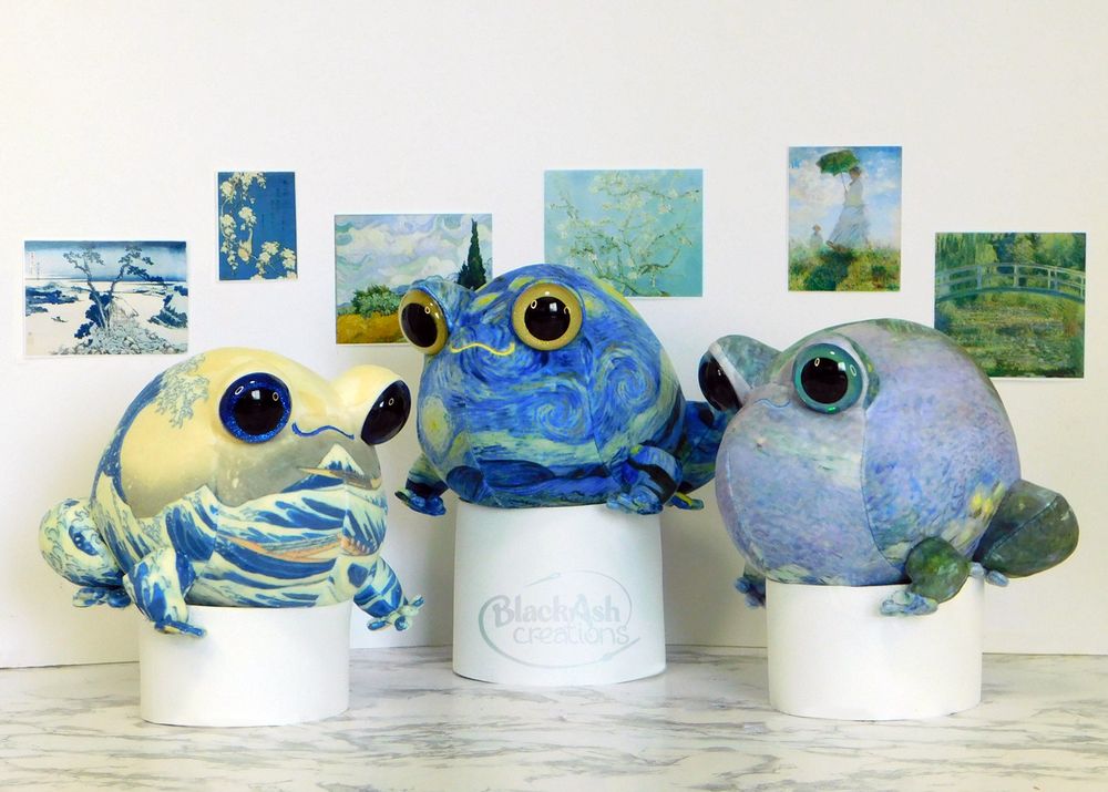 #plushart three frog plushies on pedestals with various artwork behind them, giving them a feel of being in a museum