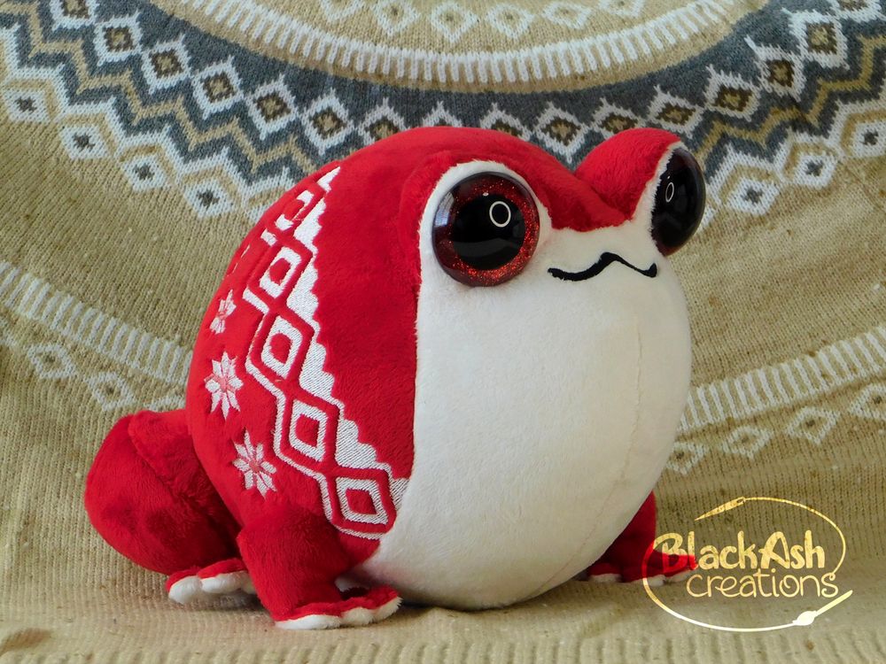 #plushart a red and white frog plush, the frog has embroidery that resembles a fair isle knitting pattern (a geometric style used in many winter sweaters)