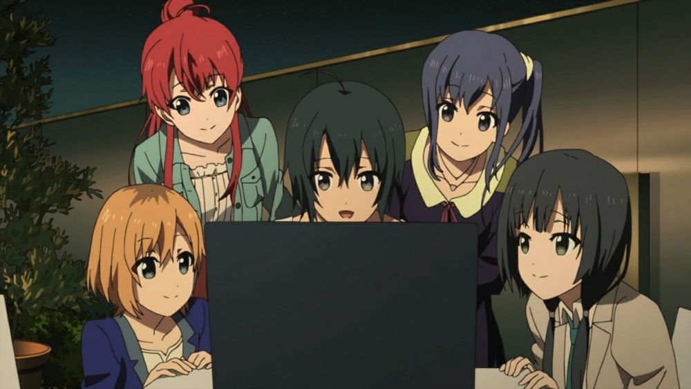 Shirobako still - the main cast members sit together around a computer.