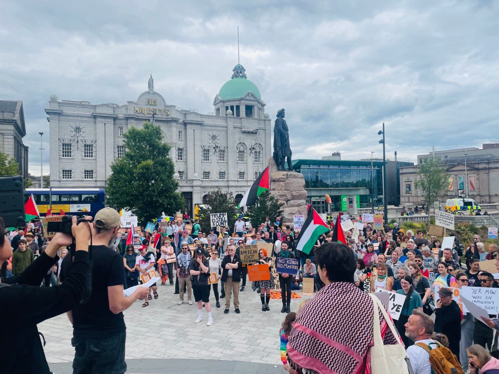A speaker addresses the rally on Union Terrace Gardens with the William Wallace Statue and His Majesty’s Theatre in the background. Several Palestinian flags can be seen in the crowd.
