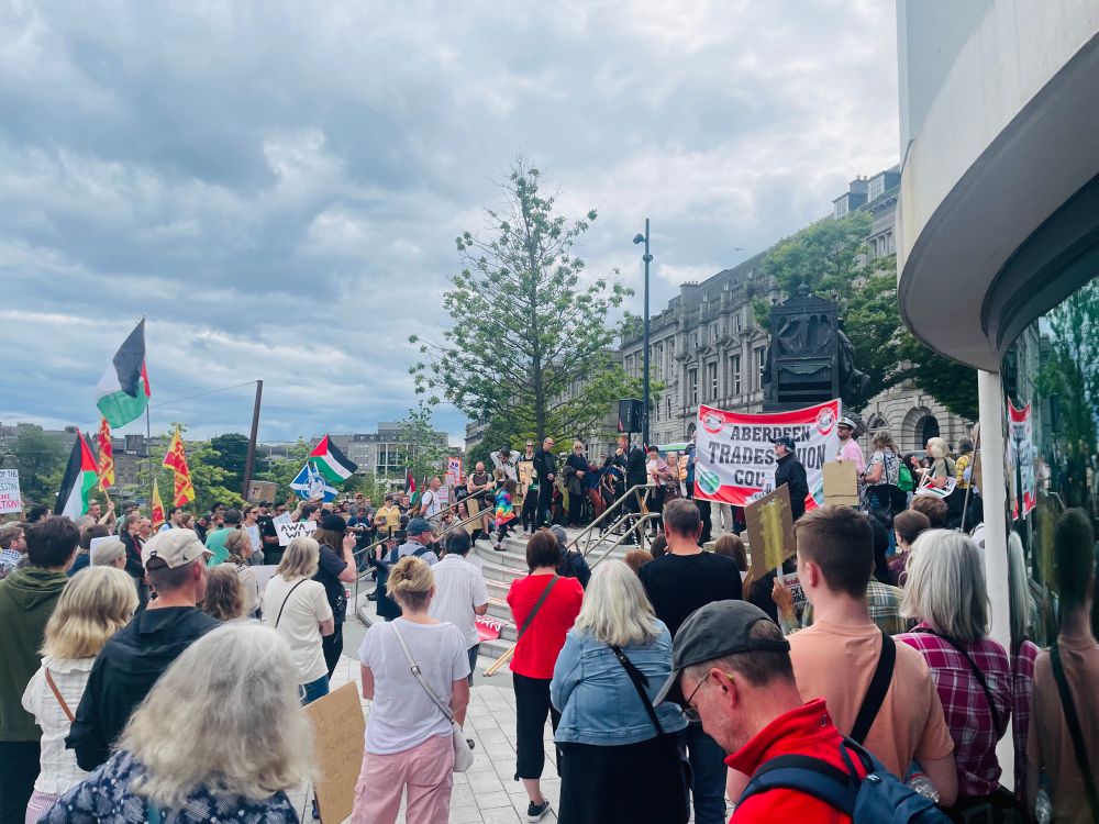 A speaker addresses the rally on Union Terrace Gardens. Several Palestinian and a Scottish flag can be seen in the crowd.