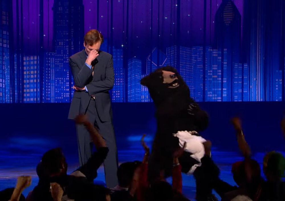 Screengrab from Late Night with Conan. The masturbating bear is on stage masturbating while Conan facepalms.