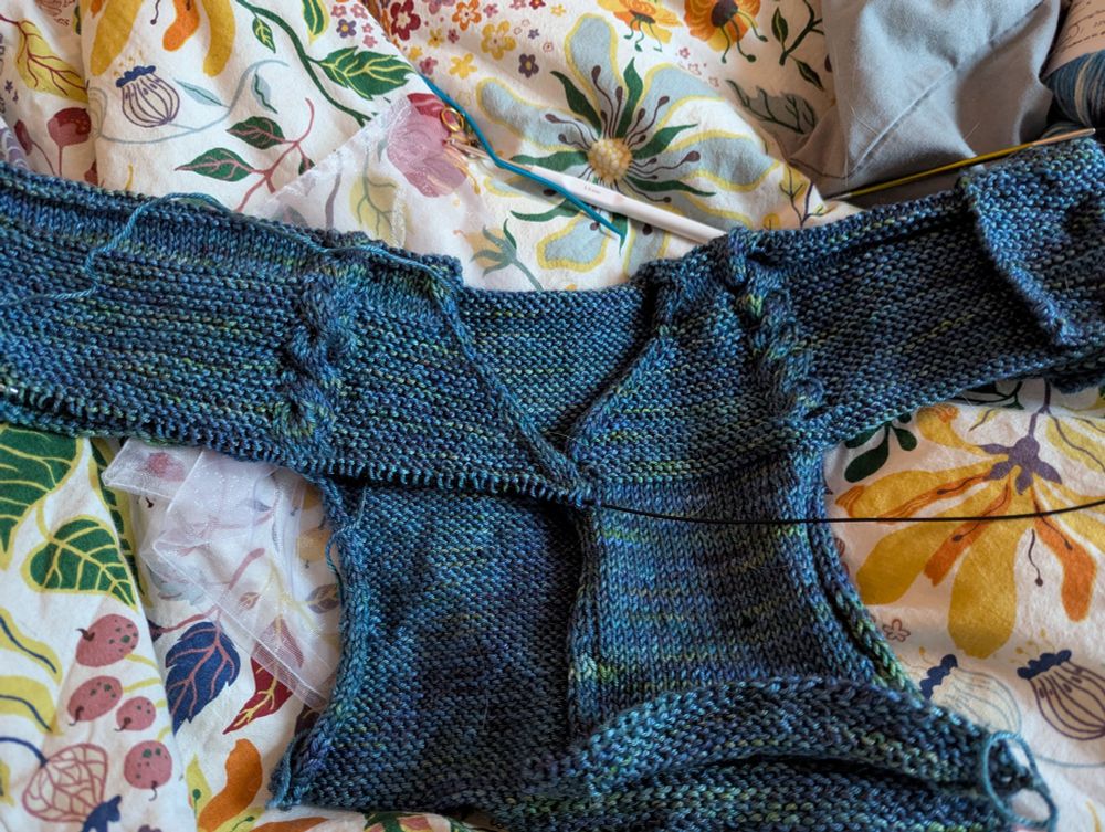 Blue-green knit on multicoloured duvet. Only half of second front completed... ran out of yarn! Ripped half of back and left front...