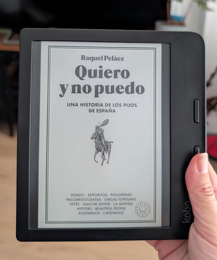 Mano sujetando un lector de libros electrónicos en cuya pantalla se ve la portada del libro "Quiero y no puedo - una historia de los pijos de España" de Raquel Peláez 
