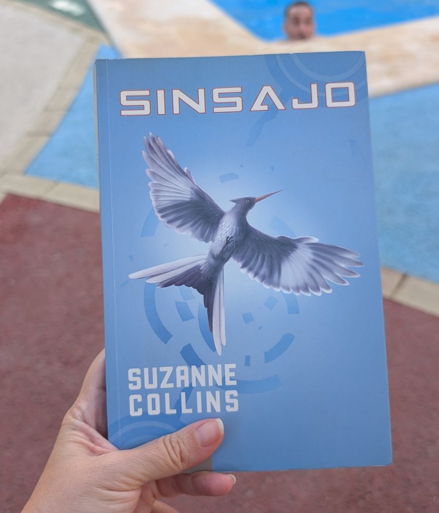 Mano sujetando el libro "Sinsajo" de Suzanne Collins