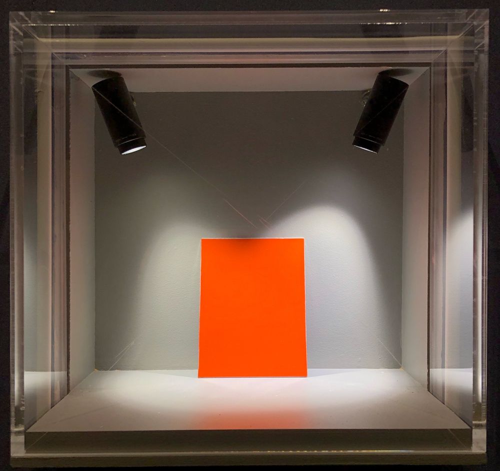 an orange colored pane inside a glass cube with lighting from top