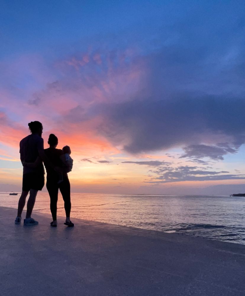 My son, wife and me standing on the beach in front of the sea. Theres a sondowner in the background and we‘re standing in its shadow