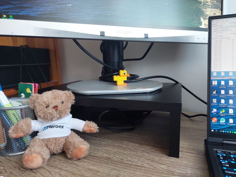 A part of my work setup. On the base of my monitor, there's Quackie, my debugging duck made of Lego, and Ecma, the official mascot bear of the JSHeroes conference. 