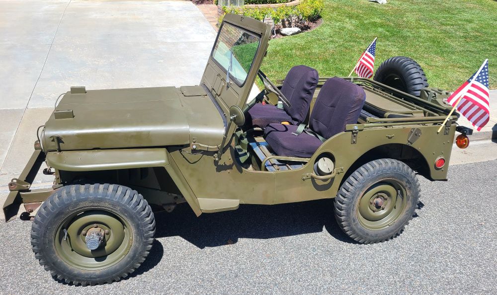 A 75 year old restored military Jeep with 2 American Flags flying from the back.