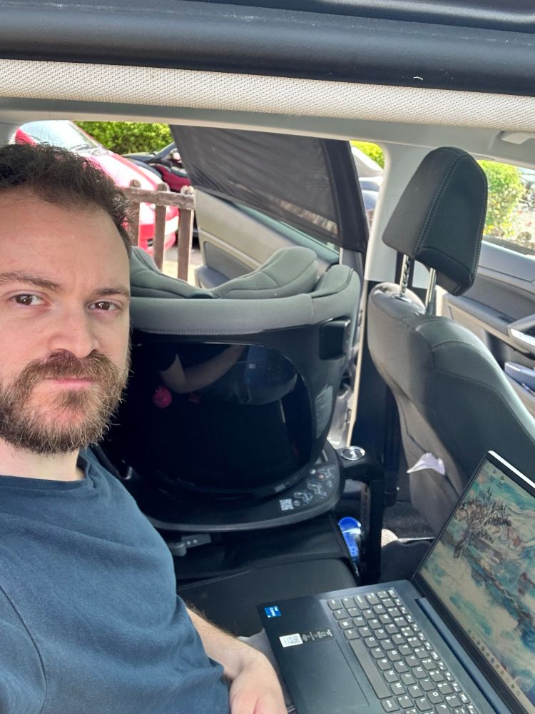 Me, disgruntled but still very handsome, working on my laptop from the backseat of my car