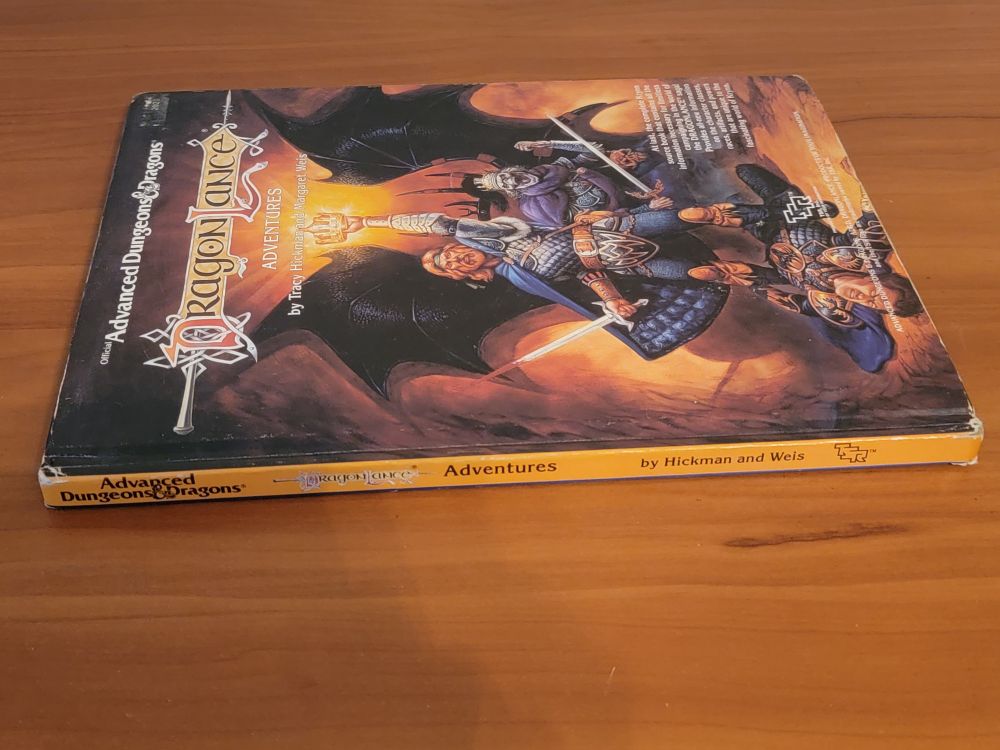 AD&D Dragonlance Adventures book shown from the spine; you can see some wear on the top and bottom of the spine where the book is mildly damaged from use.