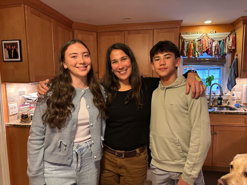 A loving mother between her girl and boy. The mom is barely shorter than the kids. 