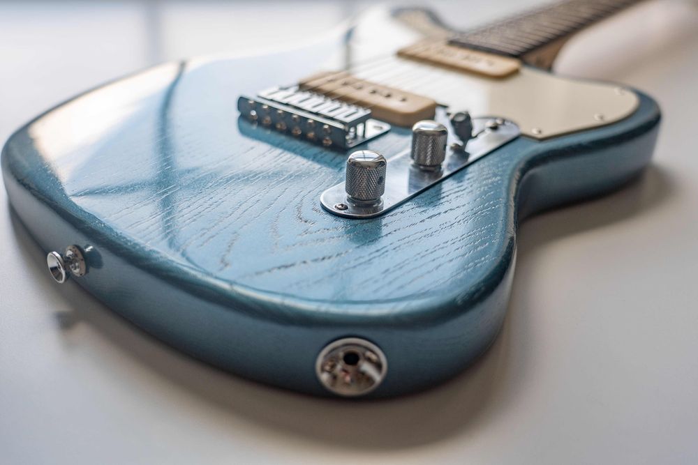 A teal blue offset electric guitar, detail shot. 