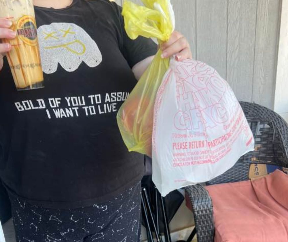 a photo of me holding a food delivery wearing a shirt with a crudely drawn ghost and the words "bold of you to assume I want to live" printed on it