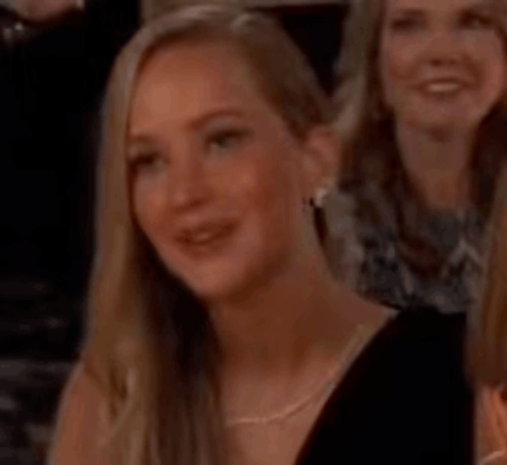 a woman in a black dress is clapping her hands in a crowd of people