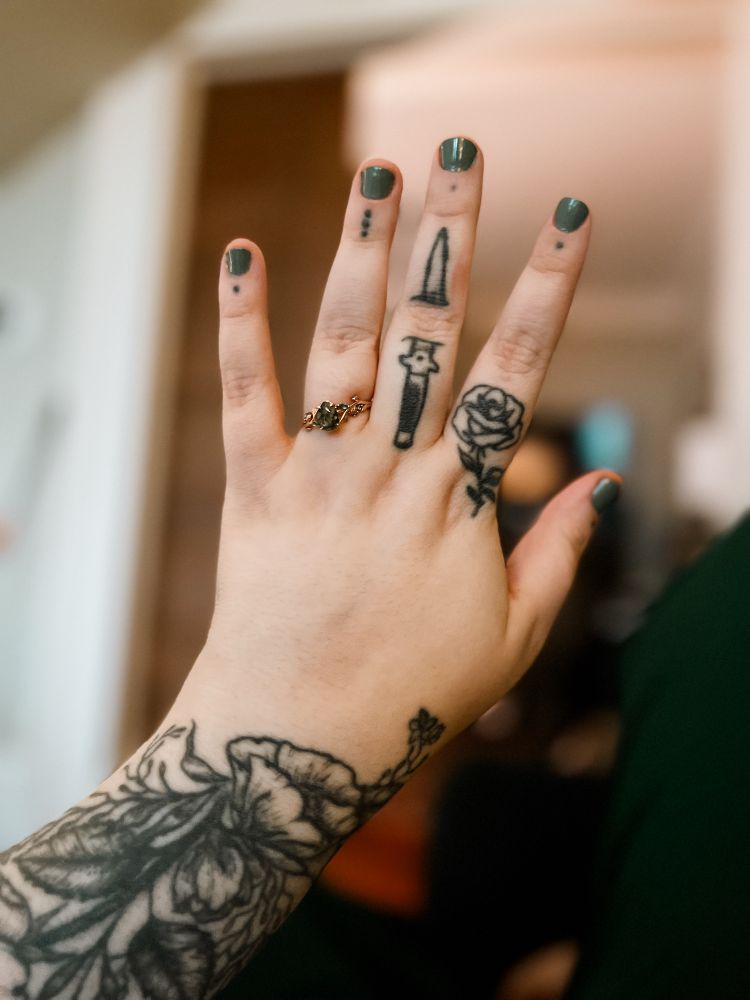 Heavily tattooed hand with engagement ring 