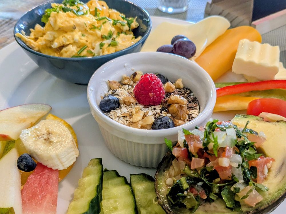 1 großer Teller mit reichhaltigem Café-Frühstück. Rührei, Avocado, Müsli usw.