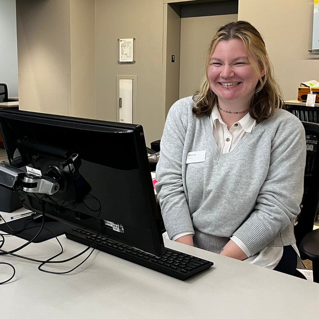 Women sitting and smiling at Guest Services Desk.