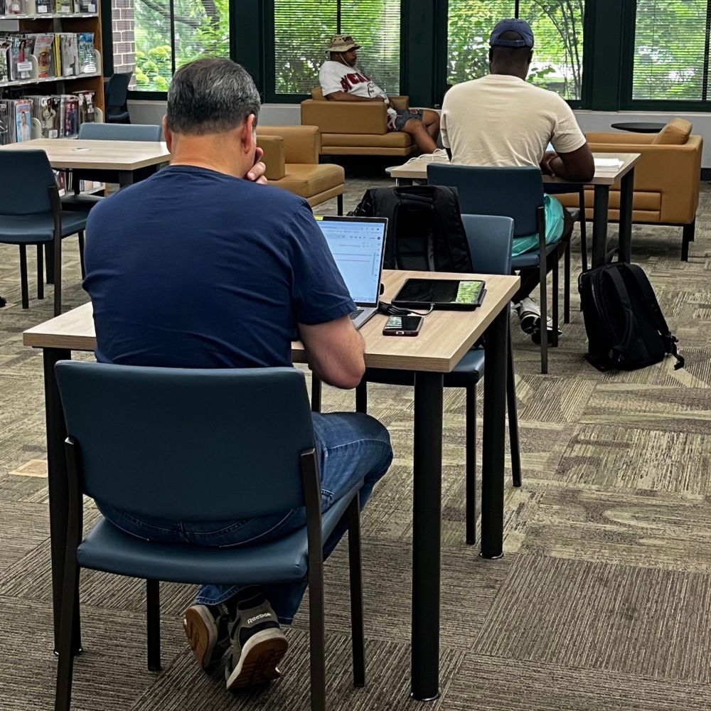 Two people sitting at tables working off their computers.