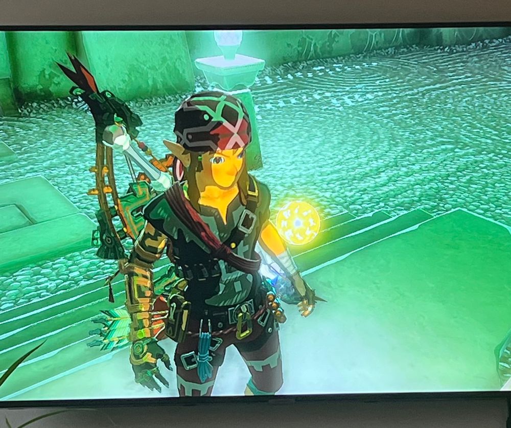 video game on television showing link in front of a ball of light 