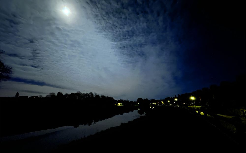 Streetlights and the Lancaster Canal while the Moon shines through cloud cover