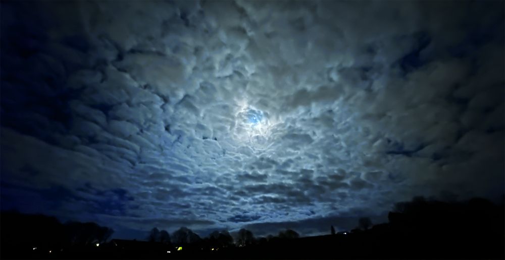 House lights below the Moon shining through clouds on the Lancaster Canal