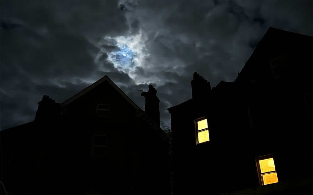 Moonlight through clouds above silhouettes of 19th century homes near the Lancaster Canal