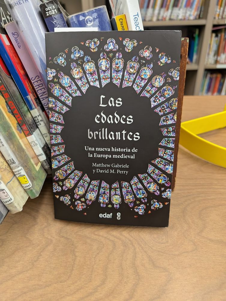 Cover of Las edades brillantes by Matthew Gabriele and David M. Perry. The cover shows stained glass windows arranged in a circle. The cover is lovely 