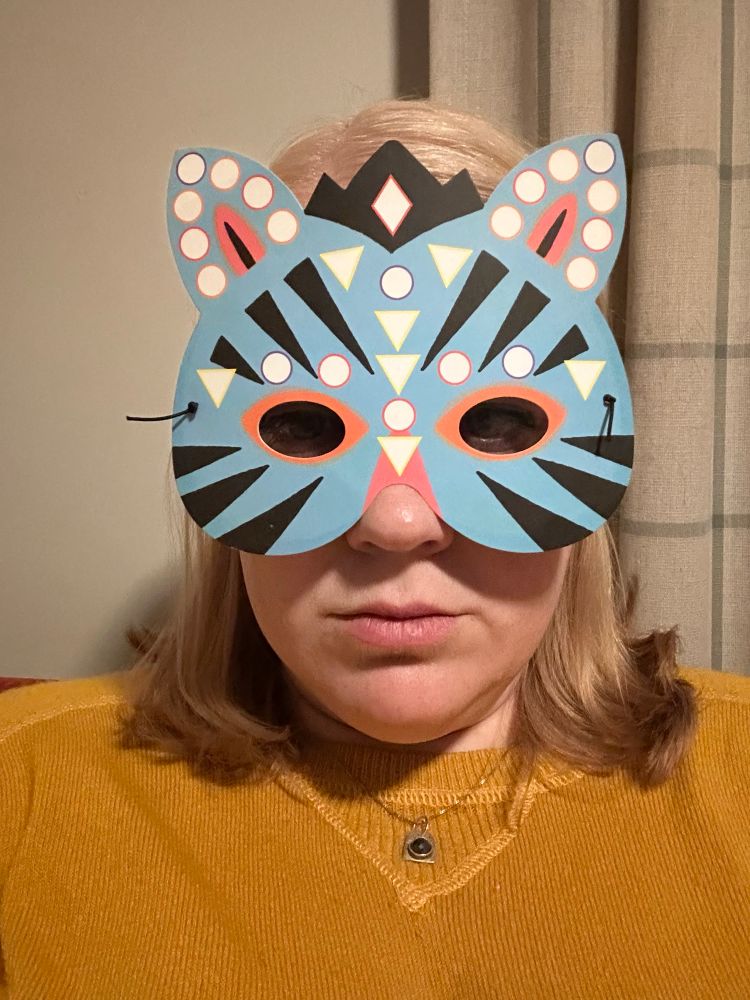 A tired mom wearing a yellow sweater and a Zebra mask that she was instructed to wear but forgot about. 