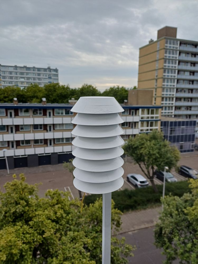 Stevenson screen on a piece of square aluminium pipe, urban cityscape with flats in the background
