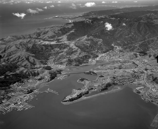 Black and white aerial photo: You are flying northwest over Richardson Bay, approaching Mill Valley. Sausalito to the left and Strawberry to the right are seen in your immediate view; Drake’s Bay and Point Reyes are seen in the distance along Marin’s west coast.