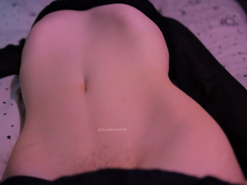 a picture of me lying on my bed with my tummy out and hips showing with my rib cage peeking out from under a black mesh crop top :)