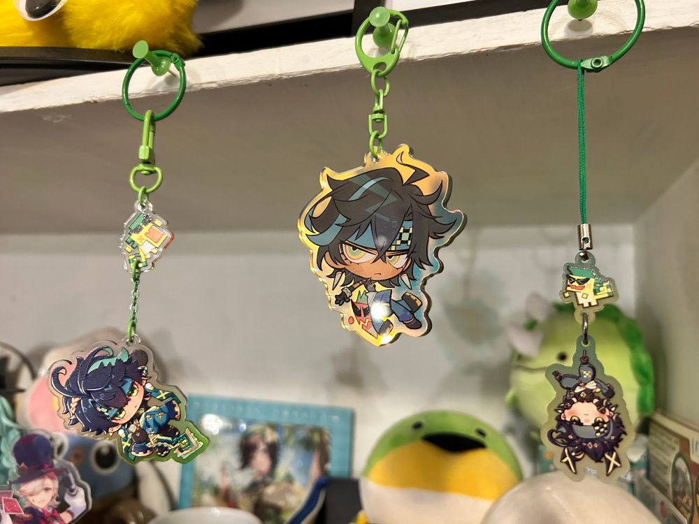 Green Kinich charms hanging from my bookshelf. They have have Ajaw (the littler pixel) in various forms of torture as Kinich is chilling