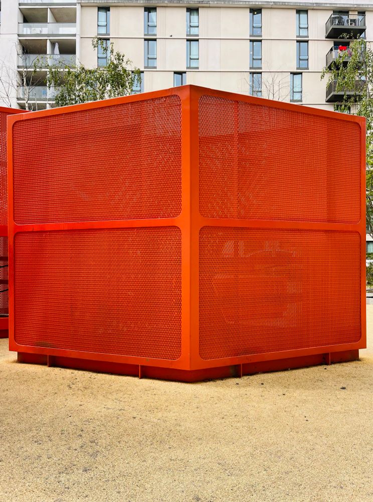 A tomato orange box in front of some ugly new build flats 