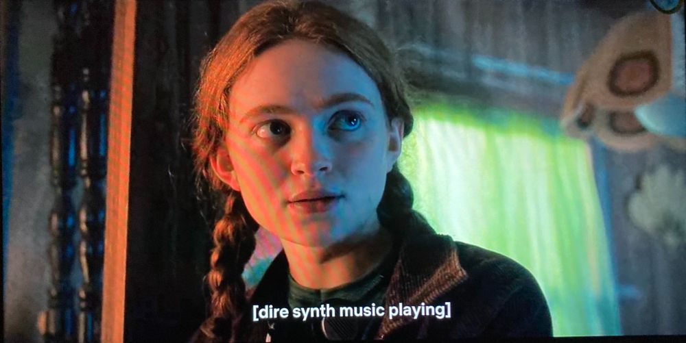 A still of Sadie Sink as Max in Stranger Things with a subtitle which reads "dire synth music playing"