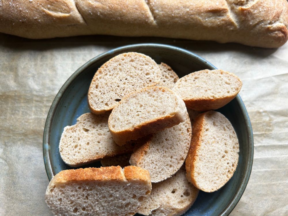rather handsome french bread loaf with a second sliced and in a bowl
